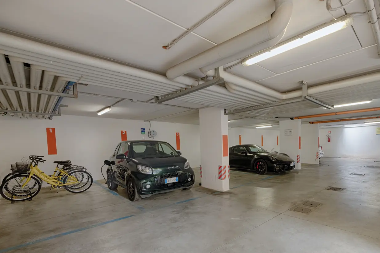 Ampio garage privato dell'Albergo Fontana a Verona con diverse auto parcheggiate in posti riservati, un ambiente sicuro e coperto con accesso diretto all'hotel.
