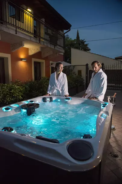 Ospiti che si rilassano nella sauna dell'Albergo Fontana a Verona durante le ore serali, con illuminazione soffusa che crea un'atmosfera calda e rigenerante.