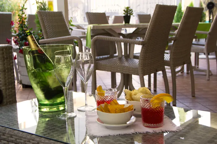 Tavoli allestiti per l'aperitivo nel dehors esterno dell'Albergo Fontana a Verona, un ambiente elegante e fiorito dove gustare cocktail e vini locali in totale relax.